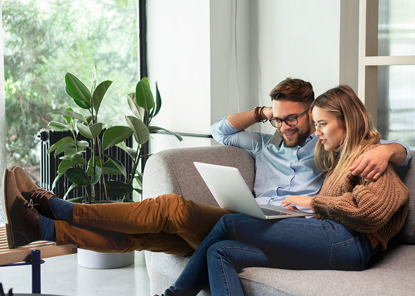 Young couple sitting on couch and reviewing their retirement plan.